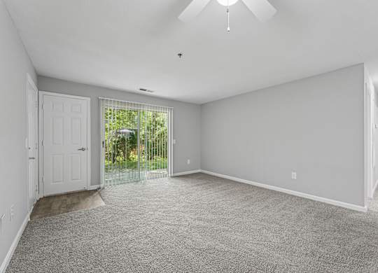 A spacious room with a carpeted floor and a ceiling fan.